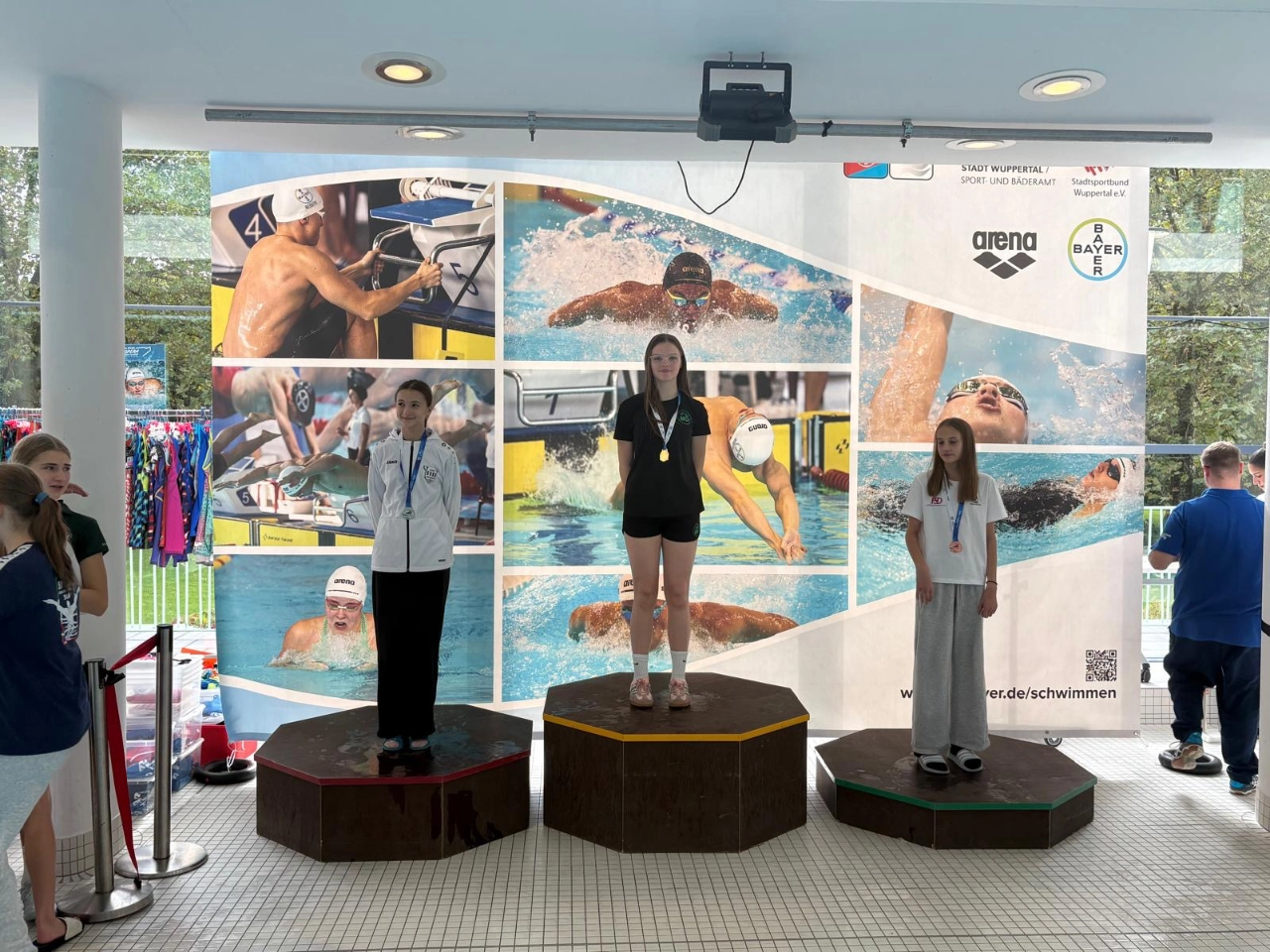 SGMG-Schwimmerin bei der Siegerehrung in Wuppertal SGMG-Schwimmerin mit Goldmedaille auf dem Siegerpodest bei den Bezirkskurzbahnmeisterschaften 2026 in Wuppertal