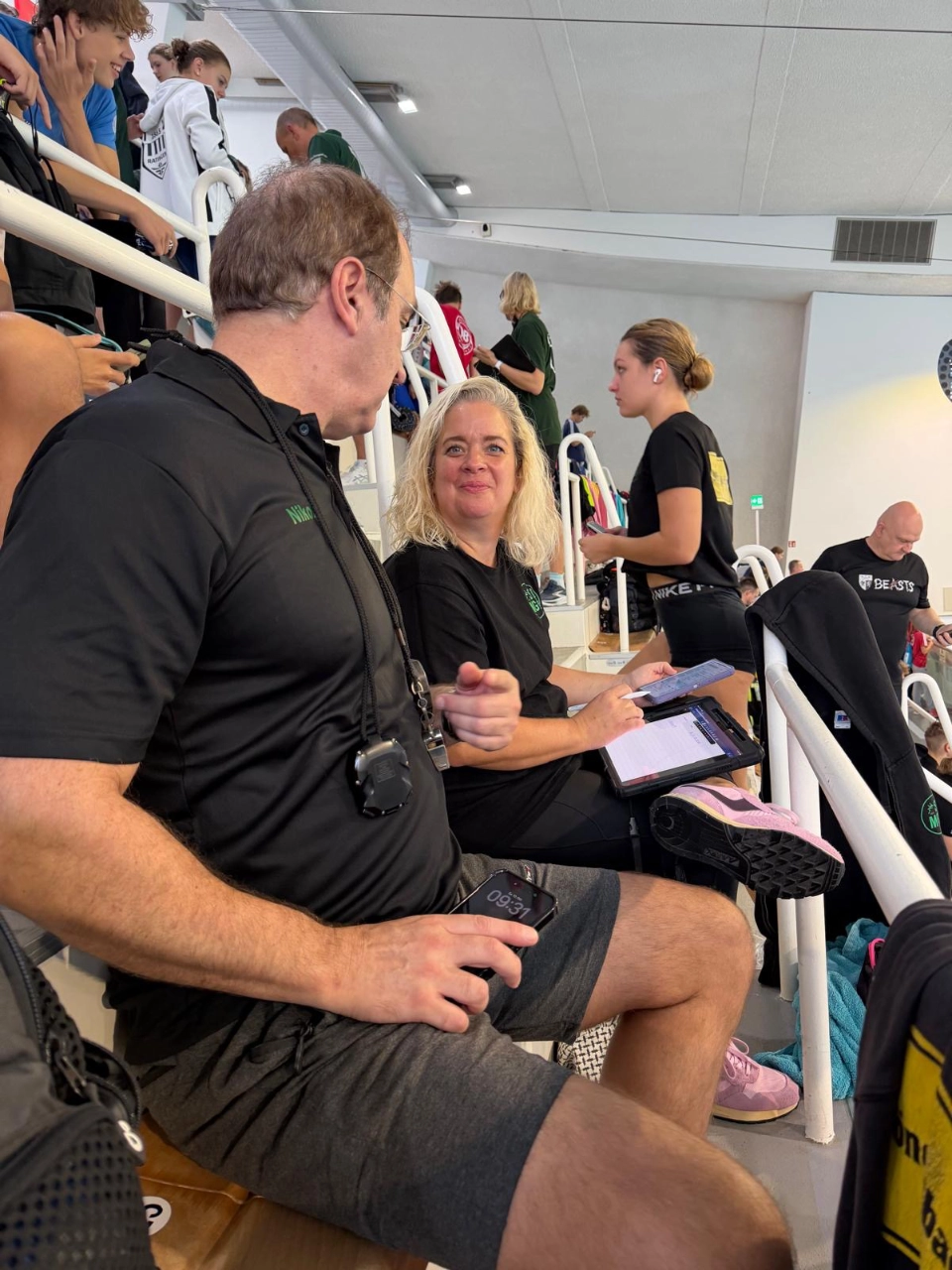 SGMG-Trainerteam bei den Bezirkskurzbahnmeisterschaften Zwei Mitglieder des SGMG-Trainer- und Betreuungsteams auf der Tribüne mit Tablets während des Schwimmwettkampfs in Wuppertal