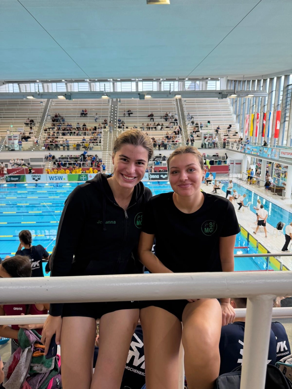 SGMG-Schwimmerinnen in der Schwimmoper Wuppertal Zwei Schwimmerinnen der SG Mönchengladbach sitzen auf der Tribüne vor dem Wettkampfbecken der Schwimmoper Wuppertal