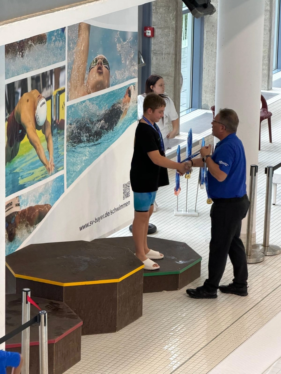 Schwimmer erhält bei der Siegerehrung der Bezirkskurzbahnmeisterschaften 2026 in Wuppertal eine Medaille Schwimmer erhält bei der Siegerehrung der Bezirkskurzbahnmeisterschaften 2026 in Wuppertal eine Medaille